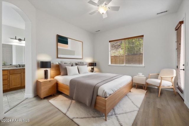 bedroom featuring ensuite bath, ceiling fan, sink, and light wood-type flooring