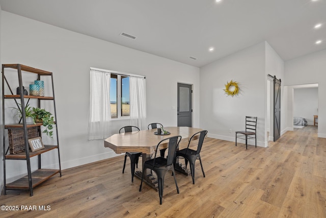 dining space featuring a barn door and light hardwood / wood-style floors