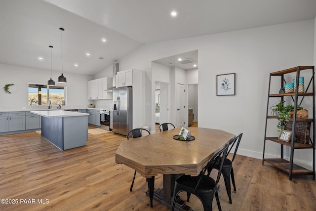 dining space featuring lofted ceiling and light hardwood / wood-style flooring