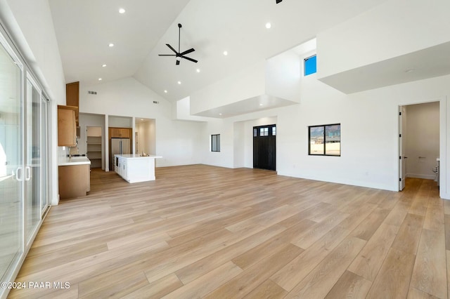 unfurnished living room with light hardwood / wood-style floors, high vaulted ceiling, ceiling fan, and a healthy amount of sunlight