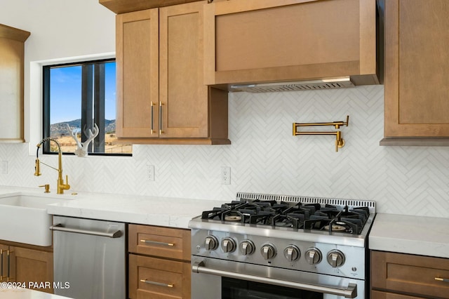 kitchen with sink, wall chimney exhaust hood, stainless steel appliances, tasteful backsplash, and light stone counters