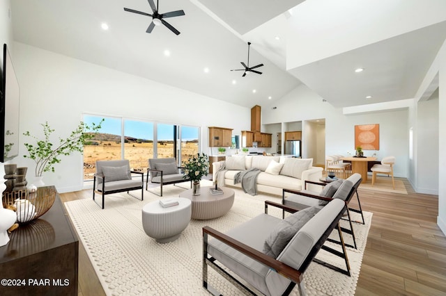 living room featuring light hardwood / wood-style flooring, high vaulted ceiling, and ceiling fan