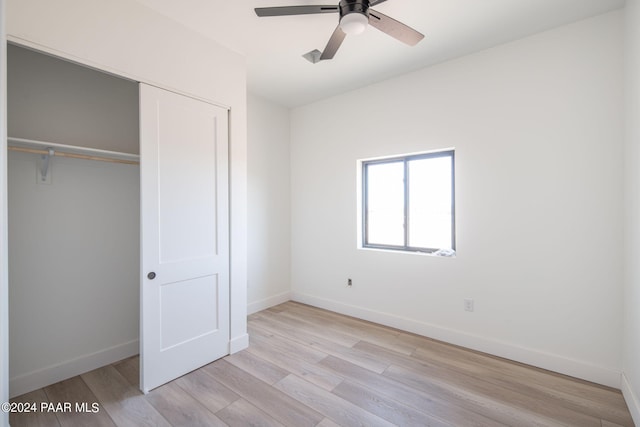 unfurnished bedroom featuring ceiling fan, light hardwood / wood-style floors, and a closet