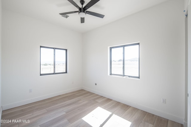 spare room featuring ceiling fan, light wood-type flooring, and a wealth of natural light