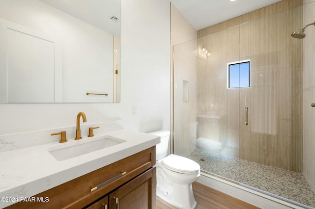 bathroom with vanity, hardwood / wood-style flooring, toilet, and a shower with shower door