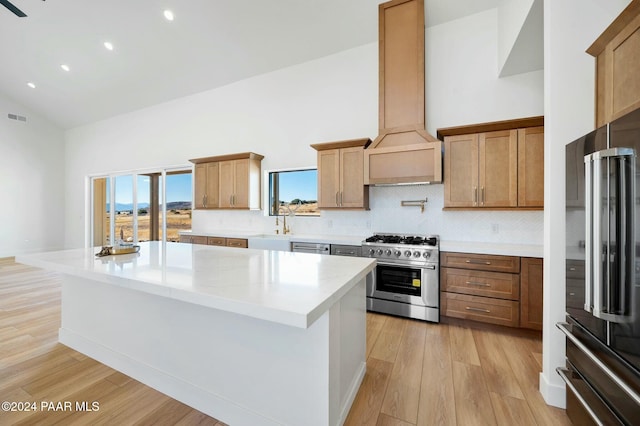 kitchen with a center island, premium appliances, light hardwood / wood-style floors, and premium range hood