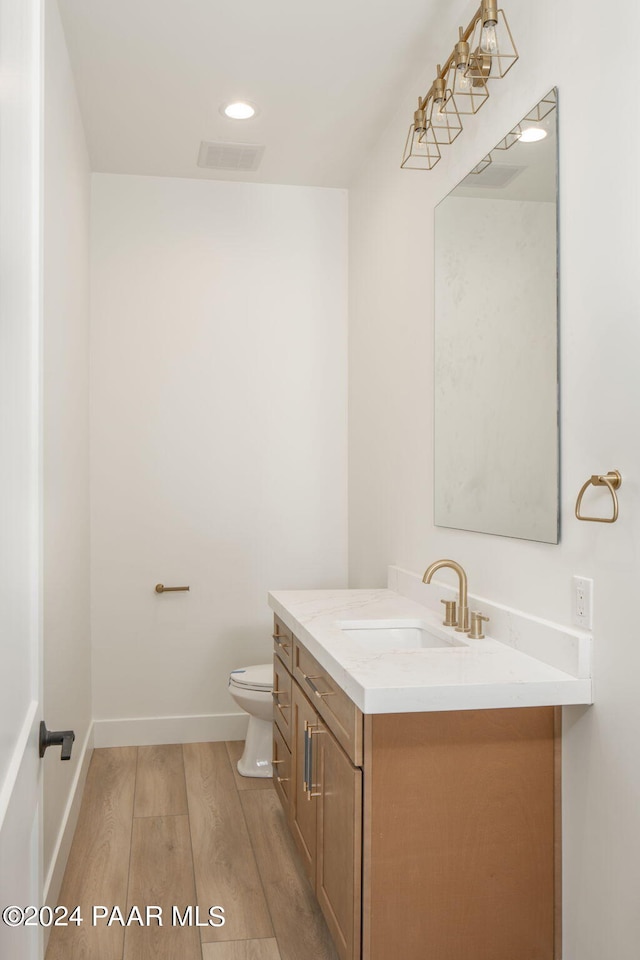 bathroom with hardwood / wood-style floors, vanity, and toilet