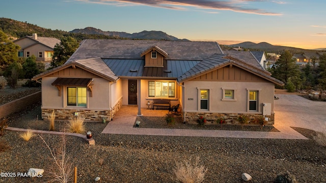 view of front facade featuring stone siding, metal roof, a standing seam roof, and a mountain view