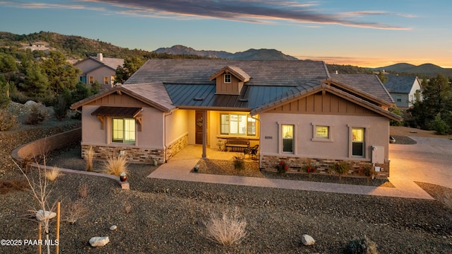 view of front facade with stone siding, a mountain view, stucco siding, and a standing seam roof