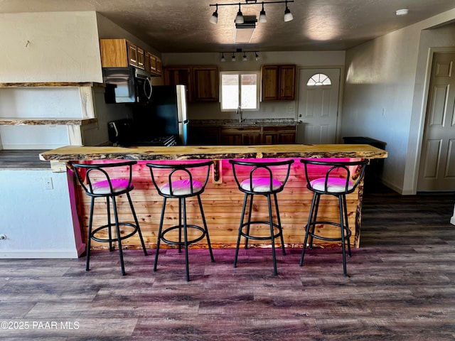 kitchen featuring dark hardwood / wood-style flooring, sink, stove, and a breakfast bar