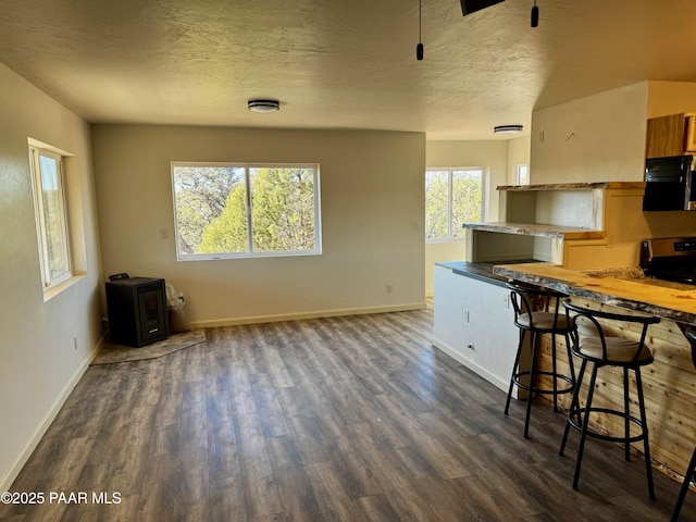 kitchen featuring a kitchen bar, electric stove, a textured ceiling, dark hardwood / wood-style flooring, and kitchen peninsula