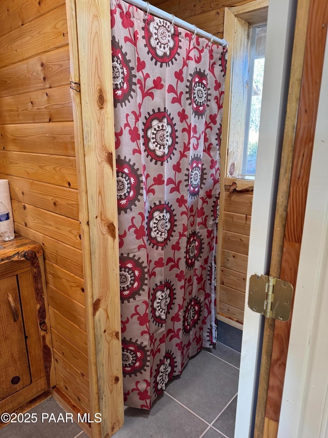 bathroom with tile patterned floors and wood walls