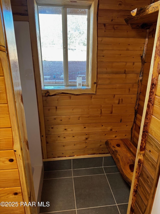 interior space with tile patterned flooring and wood walls