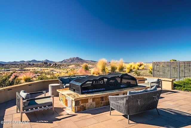 view of patio featuring fence, a mountain view, and an outdoor living space