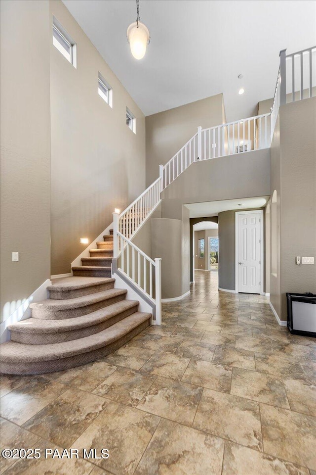 stairway featuring a high ceiling and a wealth of natural light