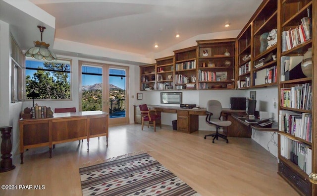 office area with lofted ceiling, built in desk, and light hardwood / wood-style floors