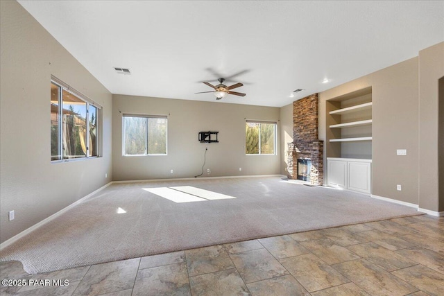 unfurnished living room featuring a healthy amount of sunlight, light carpet, built in features, and a fireplace