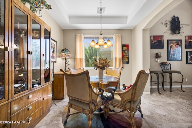 dining room with a raised ceiling and a notable chandelier