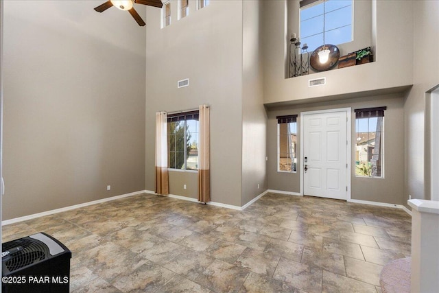 entrance foyer with ceiling fan, a healthy amount of sunlight, and a towering ceiling