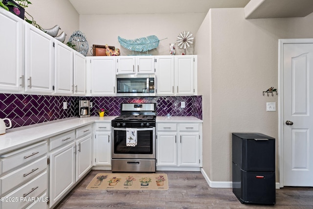 kitchen featuring stainless steel appliances, tasteful backsplash, wood finished floors, and white cabinetry