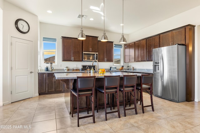 kitchen with a kitchen breakfast bar, stainless steel appliances, pendant lighting, visible vents, and dark brown cabinets