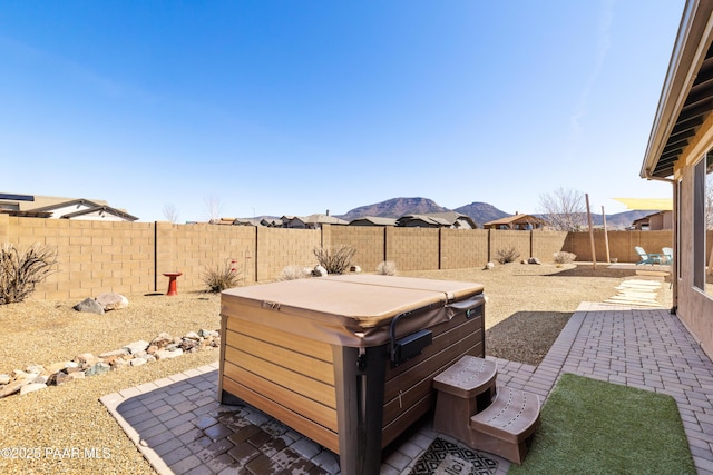view of patio / terrace with a fenced backyard, a mountain view, and a hot tub