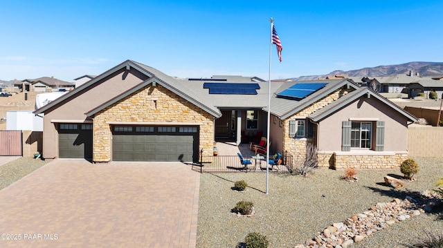 view of front of home featuring stone siding, decorative driveway, stucco siding, and fence