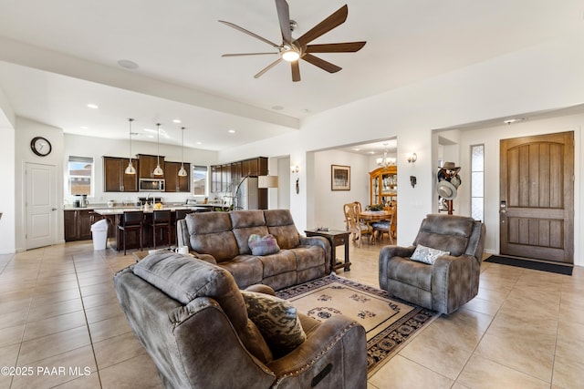 living room featuring light tile patterned flooring, ceiling fan with notable chandelier, and recessed lighting