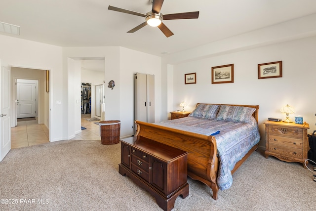 bedroom featuring light tile patterned flooring, visible vents, ceiling fan, light carpet, and a spacious closet