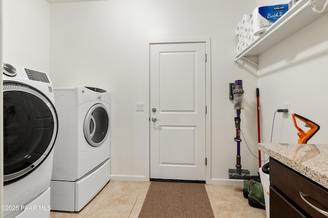 clothes washing area with light tile patterned flooring, baseboards, separate washer and dryer, and laundry area