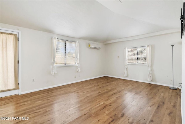 unfurnished room featuring hardwood / wood-style flooring, a wall mounted air conditioner, and a healthy amount of sunlight