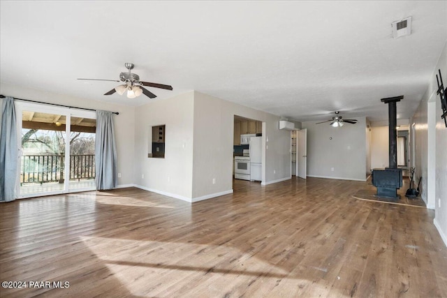 unfurnished living room featuring hardwood / wood-style flooring, ceiling fan, and a wood stove