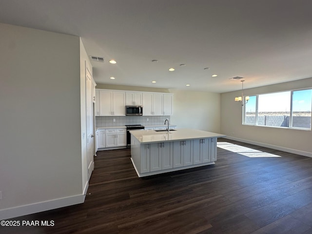 kitchen with tasteful backsplash, visible vents, dark wood-type flooring, stainless steel appliances, and a sink