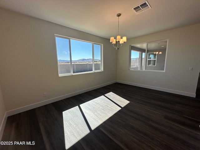 empty room with an inviting chandelier, baseboards, visible vents, and dark wood finished floors