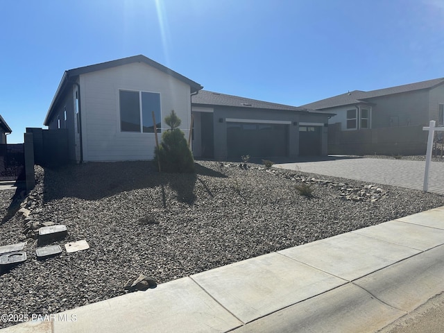 ranch-style home featuring driveway, an attached garage, and fence