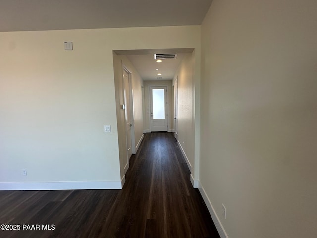 hallway featuring visible vents, dark wood finished floors, and baseboards