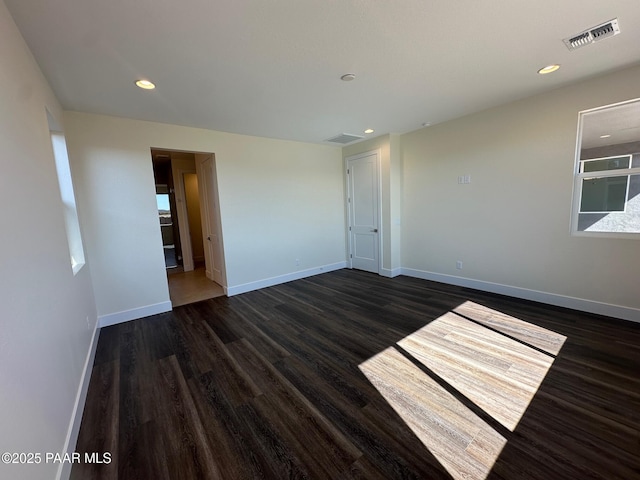 unfurnished room with wood finished floors, visible vents, and baseboards