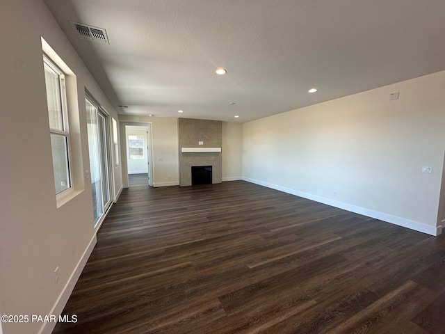 unfurnished living room featuring dark wood-style floors, baseboards, and visible vents