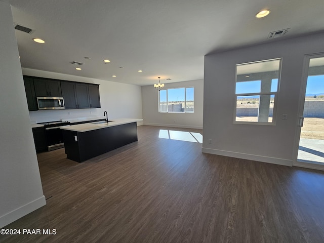 kitchen with dark wood-type flooring, plenty of natural light, an island with sink, and stainless steel appliances