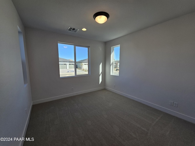 spare room featuring dark carpet