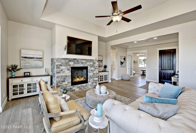 living room with ceiling fan, a fireplace, and light wood-type flooring