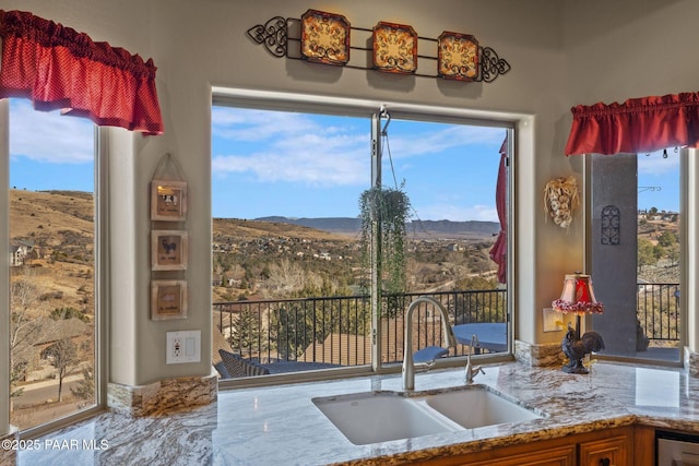 kitchen featuring light stone counters, a sink, and a mountain view