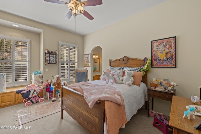 bedroom with a ceiling fan, arched walkways, and light carpet