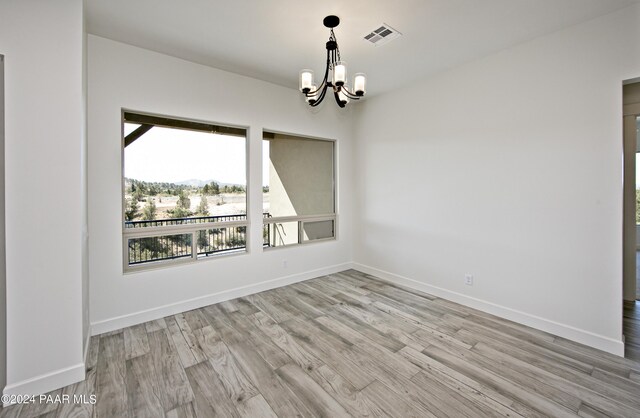 12290 N Thrine Cir, Prescott, AZ 86305 - empty room featuring baseboards, light wood-style flooring, visible vents, and an inviting chandelier