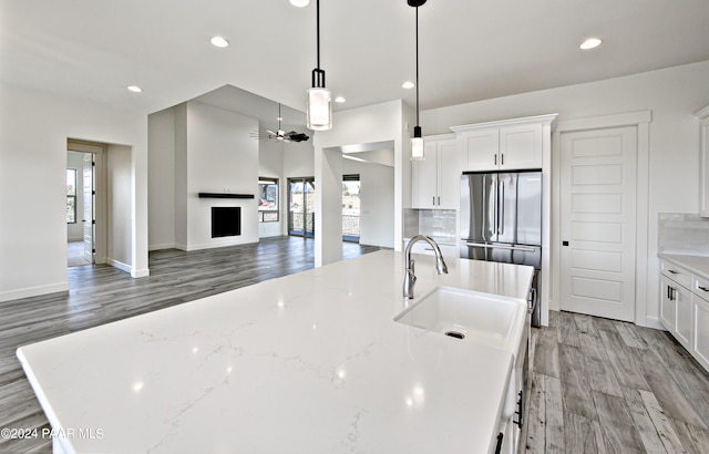 12290 N Thrine Cir, Prescott, AZ 86305 - kitchen featuring light wood-style flooring, decorative backsplash, a center island with sink, a sink, and white cabinets