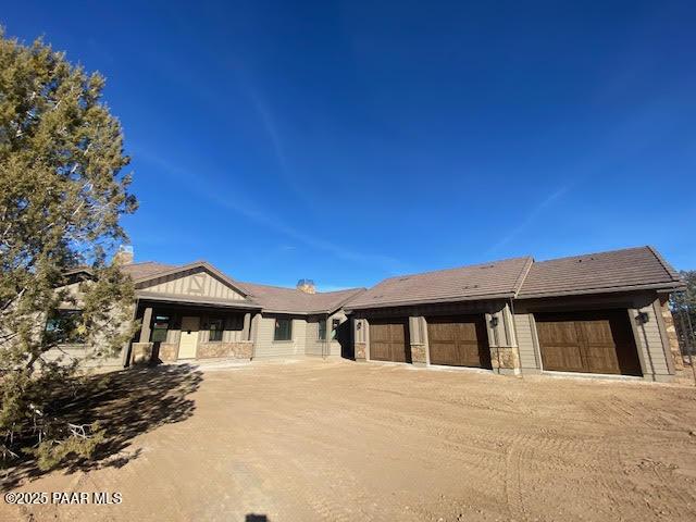 ranch-style home with a garage and dirt driveway