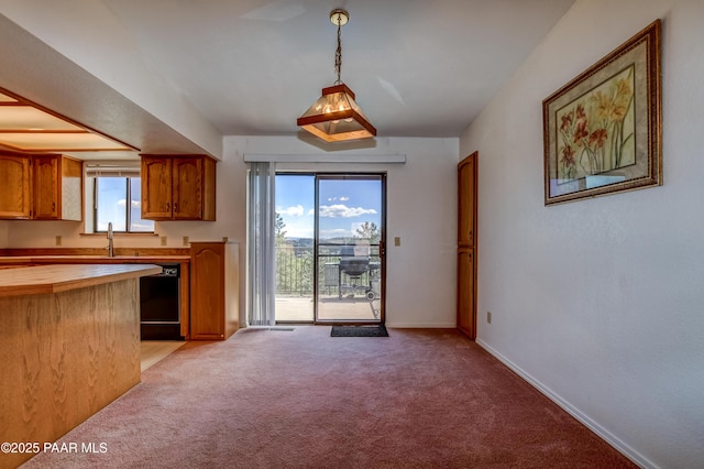 kitchen featuring brown cabinets, wood counters, baseboards, light colored carpet, and dishwasher