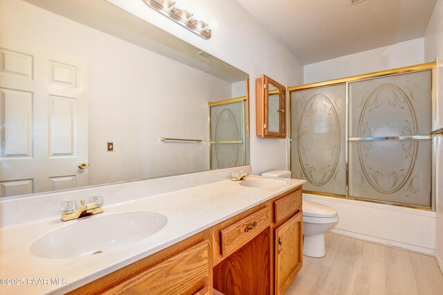 bathroom featuring double vanity, toilet, wood finished floors, and a sink