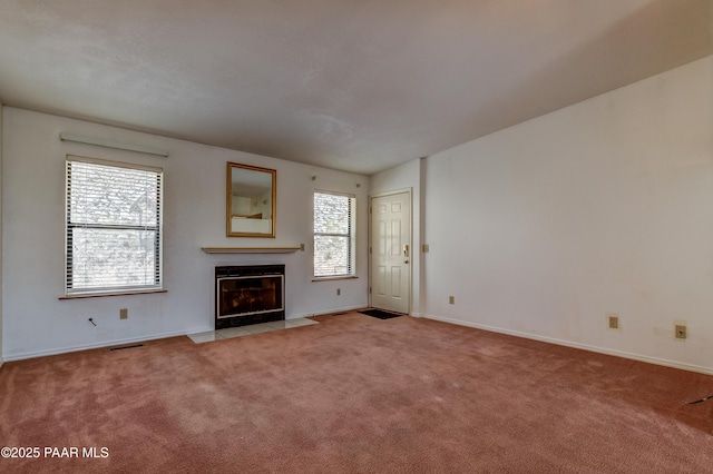 unfurnished living room featuring visible vents, light colored carpet, baseboards, and a fireplace with flush hearth