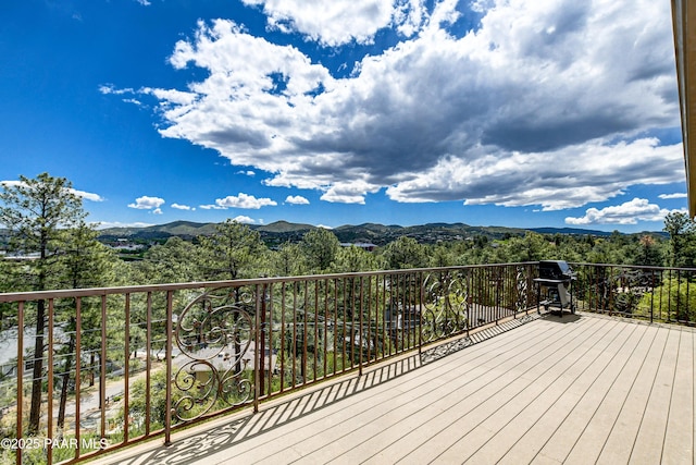 deck featuring a mountain view, a view of trees, and grilling area